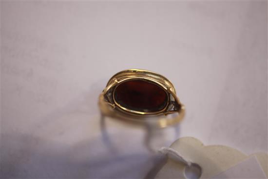 An antique yellow metal and oval carnelian cabochon ring carved with a standing bull, the shank with decorative pierced shoulders